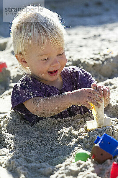 Junges Mädchen lächelnd spielen mit Schaufel  während in den Sand begraben.