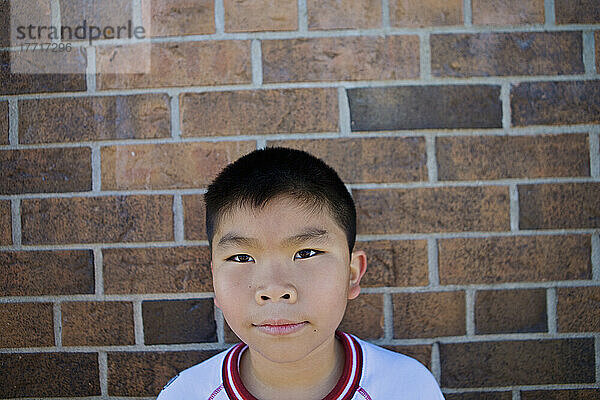 Vietnamesischer Junge gegen Backsteinmauer einer Esl-Schule; Guelph Ontario Kanada