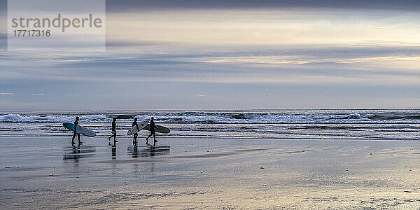 Surfer tragen ihre Surfbretter auf dem nassen Sand am beliebten Surfrevier am Long Beach  Pacific Rim National Park Reserve  Vancouver Island; British Columbia  Kanada