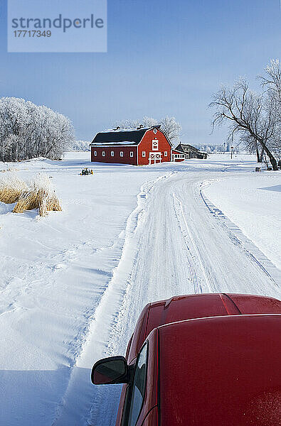 Lastwagen entlang Landweg mit roten Scheune im Hintergrund im Winter  in der Nähe von Oakbank  Manitoba