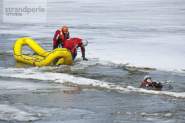 Such- und Rettungsdienstmitarbeiter tragen Überlebensausrüstung für kaltes Wasser und benutzen ein Schlauchboot bei einer Übung. Assiniboine River  Winnipeg  Manitoba  Kanada.