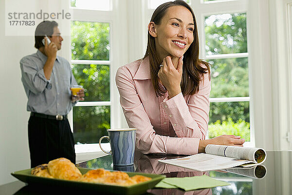 Frau mit Zeitschrift  Mann mit Handy in der Küche