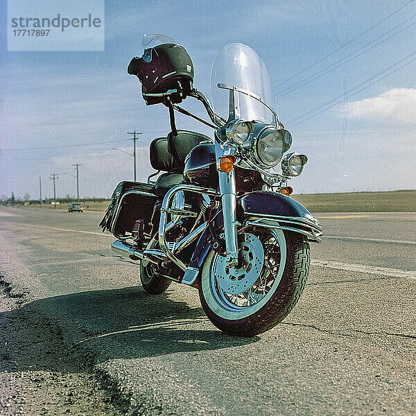 Motorrad mit Helm  geparkt am Straßenrand entlang eines Highways auf dem Land; Manitoba  Kanada