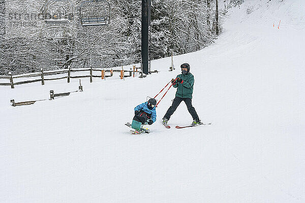 Adaptives Skifahren für ein Mädchen mit kongenitaler Ullrich-Muskeldystrophie  in einem Skigebiet mit einem Skilehrer; Canaan Valley  West Virginia  Vereinigte Staaten von Amerika