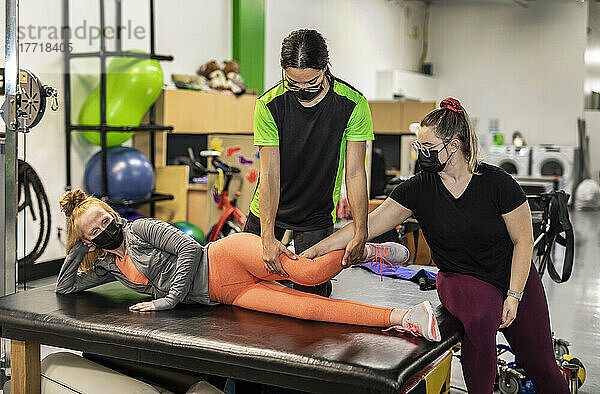 Eine querschnittsgelähmte Frau trainiert die Hüftbeugung  während ihr Trainer eine körperliche Warteschlange bildet: Edmonton  Alberta  Kanada