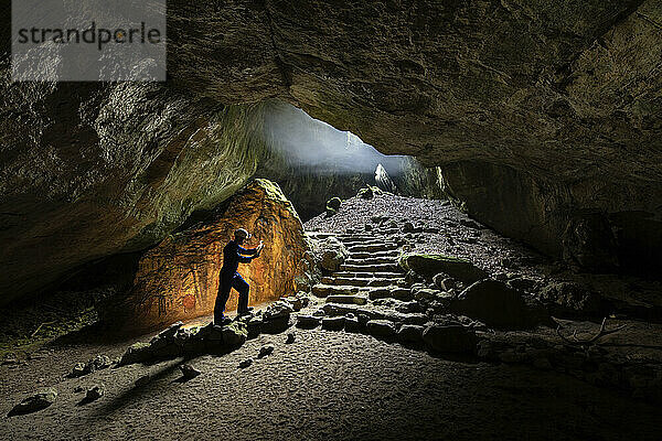 Ein wissenschaftlicher Mitarbeiter untersucht einen Knochen in der Einhornhöhle  einer historischen Schauhöhle  der größten Besucherhöhle im Westharz  Deutschland. Dieser Blick geht vom Inneren der Einhornhöhle in Richtung der Blauen Grotte. Nach der kürzlichen Entdeckung eines Knochens mit Gravuren an einer archäologischen Ausgrabungsstätte in der Nähe der Einhornhöhle dokumentiert diese Fotoserie die Ausgrabungen an der Stätte  Universität Göttingen; Westharz  Deutschland