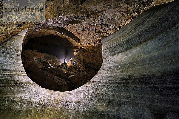 Ein Wissenschaftler klettert in der Nähe einer großen Eisschicht  die die Zeitalter und Schichten im Laufe der Zeit in der Dachstein Mammuthöhle zeigt.