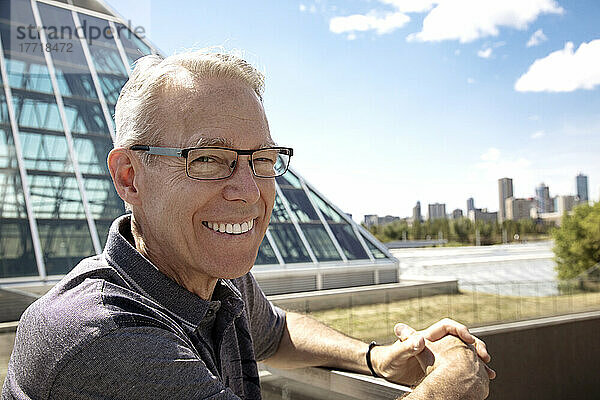 Außenporträt eines älteren Mannes mit Brille  Skyline der Stadt und moderne Architektur im Hintergrund; Edmonton  Alberta  Kanada