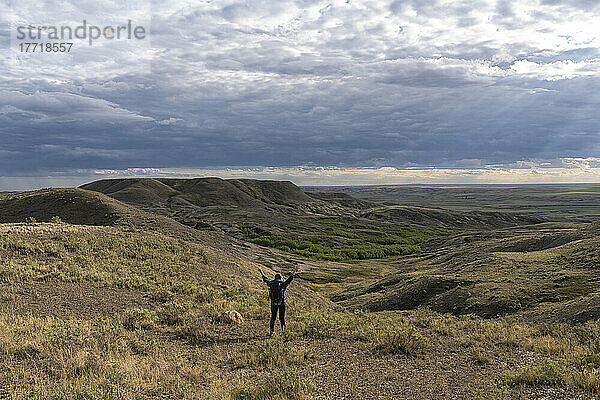 Frau steht mit erhobenen Armen vor einer schönen Aussicht im Grassands National Park; Val Marie  Saskatchewan  Kanada