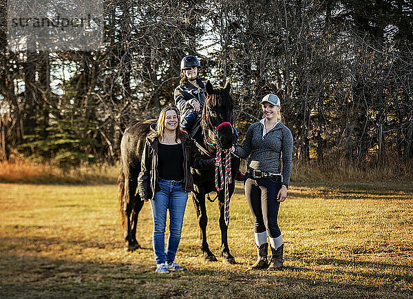 Ein junges Mädchen mit Cerebralparese posiert mit ihrer Mutter  ihrem Trainer und einem Pferd während einer Hippotherapie-Sitzung nach einem Ausritt; Westlock  Alberta  Kanada