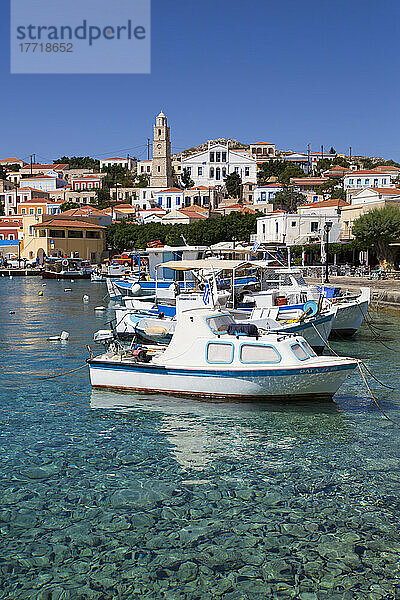 Nahaufnahme von Fischerbooten  die am Hafen von Emborio vertäut sind  mit traditionellen Gebäuden und dem Uhrenturm im Stadtzentrum auf der Insel Chalki (Halki); Dodekanes-Inselgruppe  Griechenland