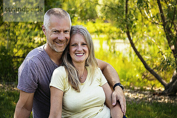 Porträt eines reifen Ehepaars im Freien  das im Gras eines Parks sitzt; Edmonton  Alberta  Kanada
