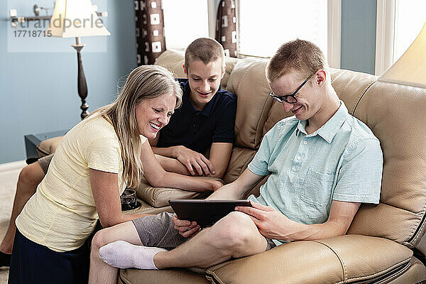 Mutter und junge erwachsene Brüder benutzen gemeinsam ein Tablet zu Hause; Edmonton  Alberta  Kanada