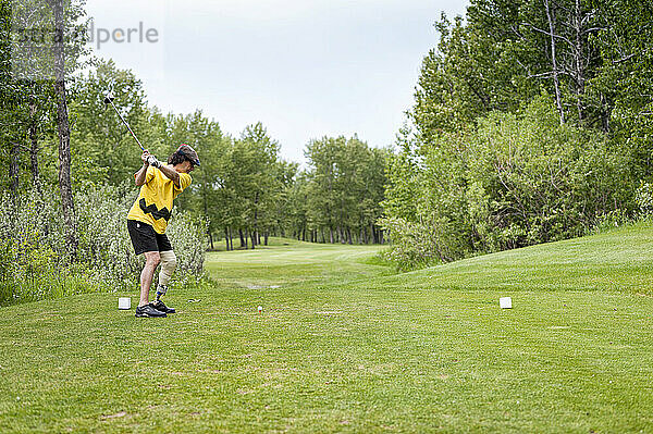 Amputierter mit Beinprothese bei einem Schlag auf dem Golfplatz; Okotoks  Alberta  Kanada