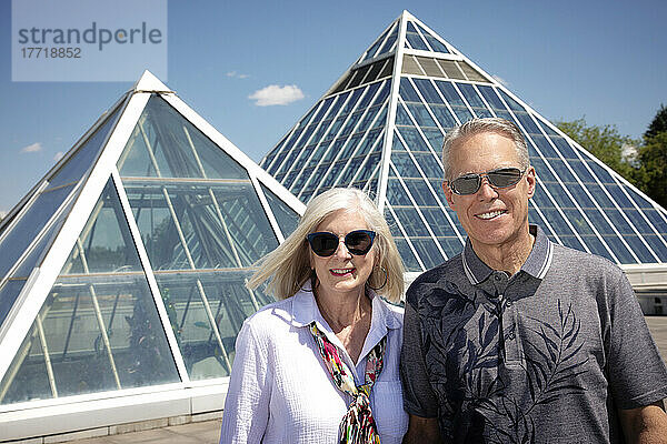 Außenporträt eines reifen Paares mit Sonnenbrille und moderner Architektur im städtischen Hintergrund; Edmonton  Alberta  Kanada