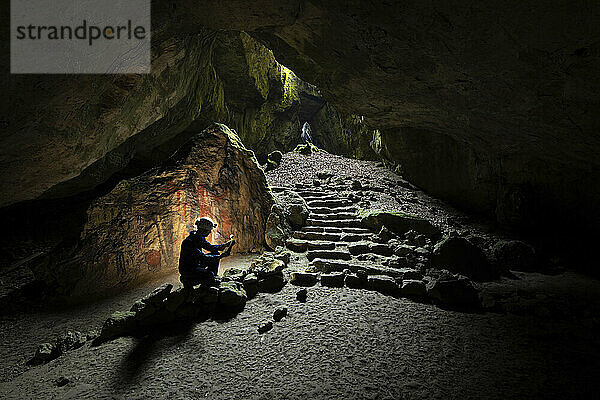 Ein wissenschaftlicher Mitarbeiter untersucht einen Knochen in der Einhornhöhle  einer historischen Schauhöhle  der größten Besucherhöhle im Westharz  Deutschland. Dieser Blick geht vom Inneren der Einhornhöhle in Richtung der Blauen Grotte. Nach der kürzlichen Entdeckung eines Knochens mit Gravuren an einer archäologischen Ausgrabungsstätte in der Nähe der Einhornhöhle dokumentiert diese Fotoserie die Ausgrabungen an der Stätte  Universität Göttingen; Westharz  Deutschland