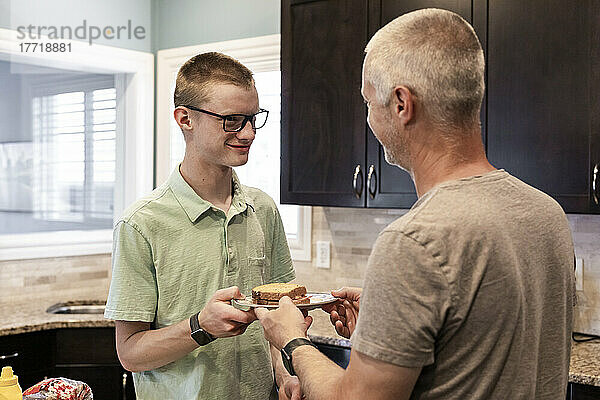 Junger Mann serviert seinem Vater ein Sandwich in der Küche zu Hause; Edmonton  Alberta  Kanada