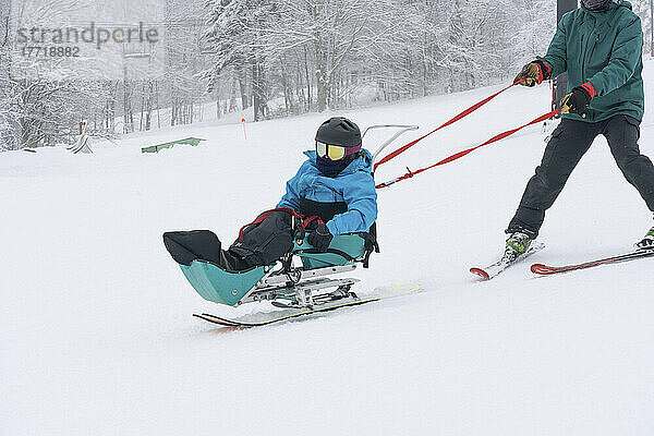 Adaptives Skifahren für ein Mädchen mit kongenitaler Ullrich-Muskeldystrophie  in einem Skigebiet mit einem Skilehrer; Canaan Valley  West Virginia  Vereinigte Staaten von Amerika