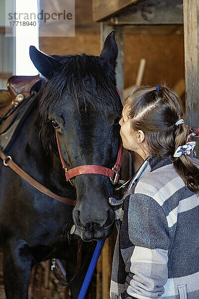 Ein junges Mädchen mit Cerebralparese küsst ein Pferd in einer Scheune während einer Hippotherapie-Sitzung; Westlock  Alberta  Kanada