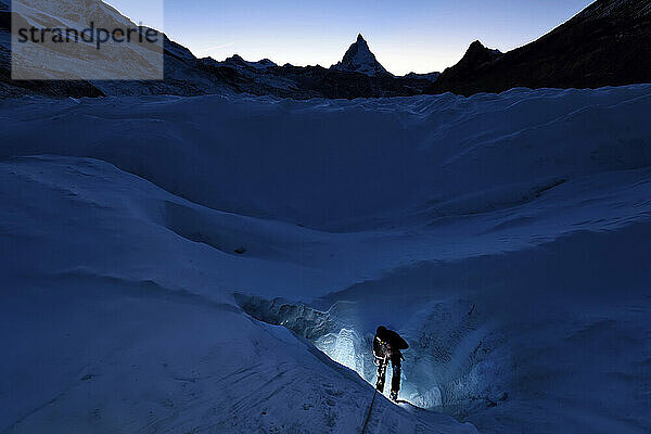 Der britische Höhlenforscher und Glaziologe taucht aus einer Gletschermühle mit dem Matterhorn im Hintergrund auf.