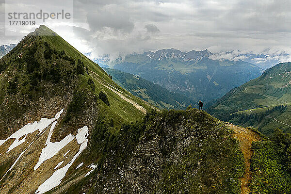 Ein Wanderer erreicht einen Berggipfel und blickt auf die herrliche Aussicht auf die Alpen bei bewölktem Himmel; Feldkirch  Vorarlberg  Österreich