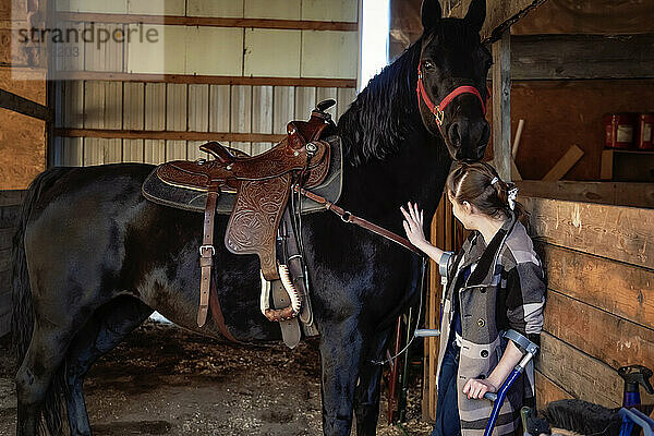 Ein junges Mädchen mit Cerebralparese mit einem Pferd in einer Scheune während einer Hippotherapie-Sitzung; Westlock  Alberta  Kanada