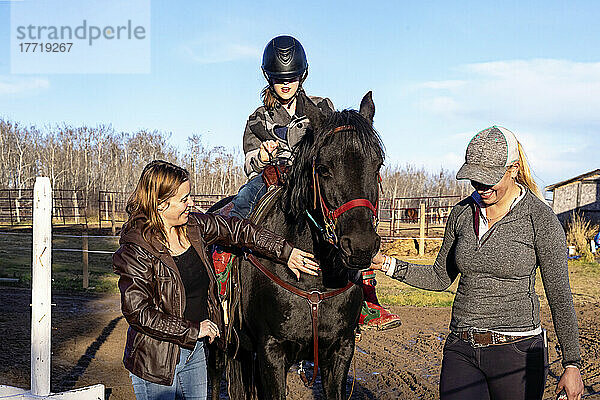 Ein junges Mädchen mit Cerebralparese  ihre Mutter und ihr Trainer arbeiten mit einem Pferd während einer Hippotherapie-Sitzung; Westlock  Alberta  Kanada