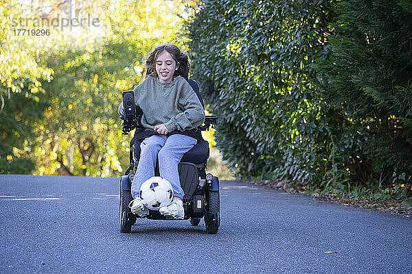 Elfjähriges Mädchen mit kongenitaler Ullrich-Muskeldystrophie spielt in ihrem Rollstuhl in der Nähe ihres Hauses Fußball; Cabin John  Maryland  Vereinigte Staaten von Amerika