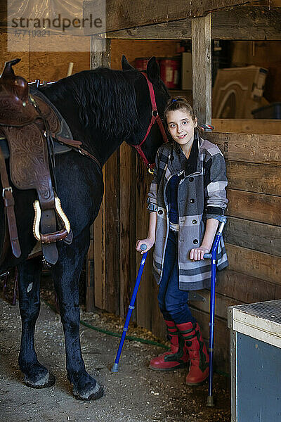 Ein junges Mädchen mit Cerebralparese mit einem Pferd in einer Scheune während einer Hippotherapie-Sitzung; Westlock  Alberta  Kanada