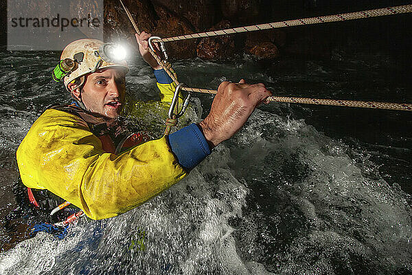 Ein Mitglied des Erkundungsteams klettert gegen den reißenden Fluss in der Ora-Höhle  während sie die wilden und gefährlichen Flusshöhlen der Nakanai-Berge auf der Insel Neubritannien  Papua-Neuguinea  erforschen; Neubritannien  Papua-Neuguinea