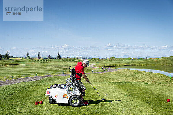 Behinderter Golfer  der einen speziellen motorisierten Hydraulik-Rollstuhl für den Golfsport benutzt; Okotoks  Alberta  Kanada