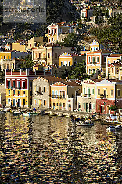 Warmes Sonnenlicht auf den farbenfrohen Gebäuden entlang der Uferpromenade im Hafen von Gialos  Insel Symi (Simi); Dodekanes-Inselgruppe  Griechenland