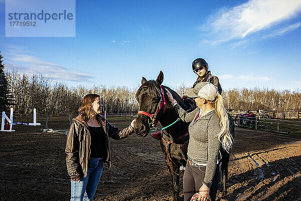 Ein junges Mädchen mit Cerebralparese  ihre Mutter und ihr Trainer arbeiten mit einem Pferd während einer Hippotherapie-Sitzung; Westlock  Alberta  Kanada