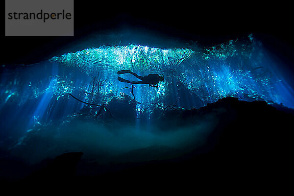 Silhouette eines Höhlentauchers bei der Erkundung einer Cenote oder eines Erdlochs; Tulum  Quintana Roo  Mexiko