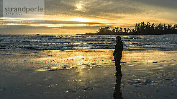 Eine Frau steht bei Sonnenuntergang am Long Beach und blickt auf den Ozean  Pacific Rim National Park Reserve  Vancouver Island; British Columbia  Kanada