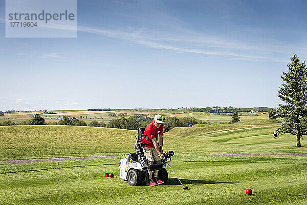 Behinderter Golfer  der einen speziellen motorisierten Hydraulik-Rollstuhl für den Golfsport benutzt; Okotoks  Alberta  Kanada