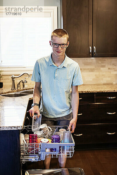 Junger Mann räumt den Geschirrspüler zu Hause aus; Edmonton  Alberta  Kanada