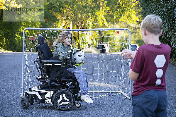 Elfjähriges Mädchen mit kongenitaler Ullrich-Muskeldystrophie spielt in ihrem Rollstuhl mit einer Freundin in der Nähe ihres Hauses Fußball; Cabin John  Maryland  Vereinigte Staaten von Amerika