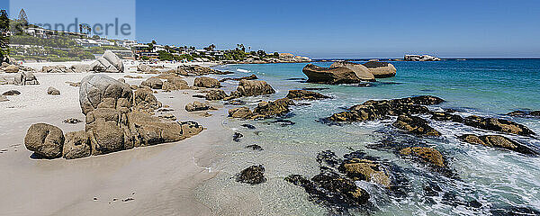 Felsiges Ufer mit großen Felsblöcken und Häusern am Strand entlang des Atlantiks am Clifton Beach; Kapstadt  Westkap  Südafrika