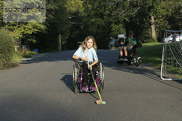 Mädchen mit kongenitaler Ullrich-Muskeldystrophie spielt in ihrem Rollstuhl Straßenhockey; Cabin John  Maryland  Vereinigte Staaten von Amerika