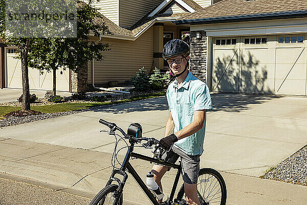 Junger Mann posiert auf seinem Fahrrad in einer Wohnstraße; Edmonton  Alberta  Kanada