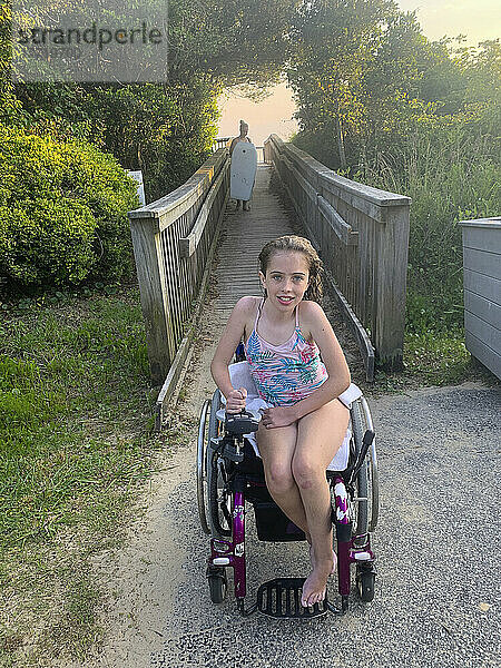 Mädchen mit kongenitaler Ullrich-Muskeldystrophie sitzt in ihrem Badeanzug in einem Rollstuhl auf einem Weg zum Strand nach einem Bad im Pamlico Sound; Nags Head  North Carolina  Vereinigte Staaten von Amerika
