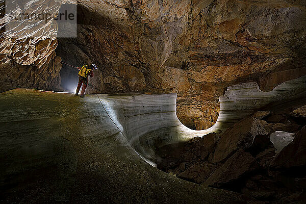 Ein Wissenschaftler klettert in der Nähe einer großen Eisschicht  die die Zeitalter und Schichten im Laufe der Zeit in der Dachstein Mammuthöhle zeigt.