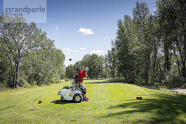 Behinderter Golfer  der einen speziellen motorisierten Hydraulik-Rollstuhl für den Golfsport benutzt; Okotoks  Alberta  Kanada