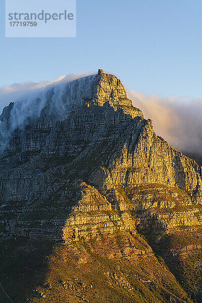 Blick auf den sonnenbeschienenen Tafelberg vom Lion's Head mit einer Wolkenformation  die einen Tischtuch-Effekt über den Berggipfeln erzeugt; Kapstadt  Westkap-Provinz  Südafrika