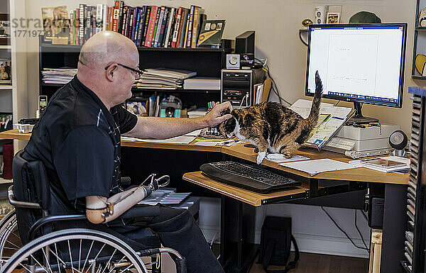 Mann mit doppelter Gliedmaßenamputation arbeitet von zu Hause aus am Computer; St. Albert  Alberta  Kanada