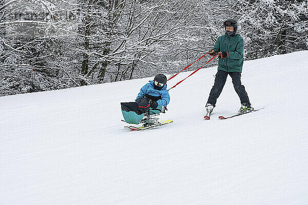 Adaptives Skifahren für ein Mädchen mit kongenitaler Ullrich-Muskeldystrophie  in einem Skigebiet mit einem Skilehrer; Canaan Valley  West Virginia  Vereinigte Staaten von Amerika