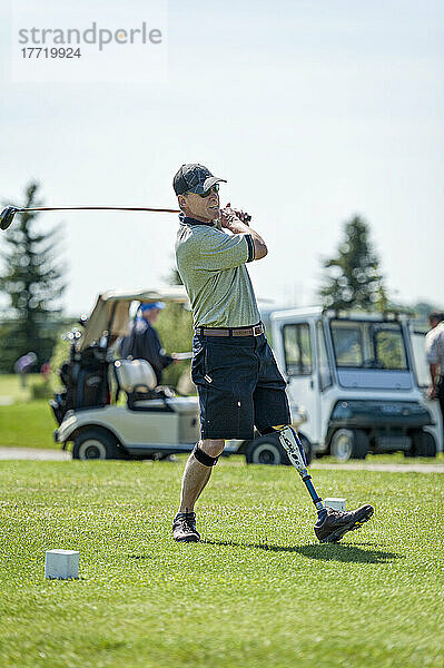 Amputierter mit Beinprothese schlägt den Ball auf dem Golfplatz; Okotoks  Alberta  Kanada