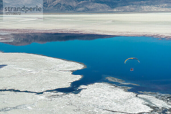 Ein Motorschirmpilot fliegt über dem Owens Lake  einem größtenteils trockenen Seebett  in der Sierra Nevada in der Nähe von Lone Pine; Lone Pine  Inyo County  Kalifornien  Vereinigte Staaten von Amerika