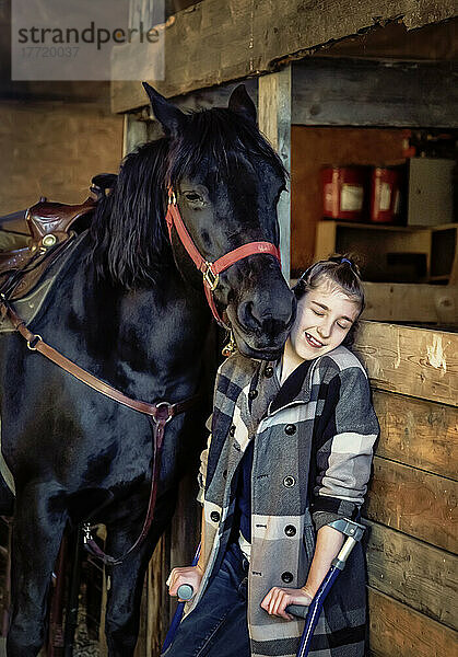 Ein junges Mädchen mit Cerebralparese mit einem Pferd in einer Scheune während einer Hippotherapie-Sitzung; Westlock  Alberta  Kanada